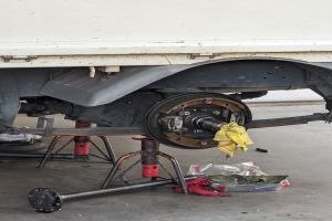 Ein gelber, tuchbedeckter Lastwagen in einer Garage mit Werkzeugen und Gegenständen, die vor ihm auf dem Boden verstreut sind.