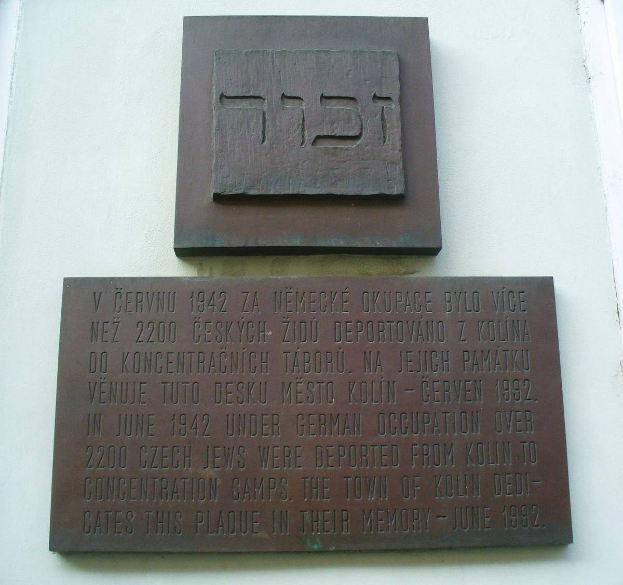 Metallgedenktafel mit hebräischer Schrift an der Seite eines Gebäudes angebracht.