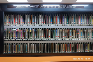 Eine gut beleuchtete Bibliothek mit hohen Regalen voller Bücher, ein Textbrett und ein Wasserzeichen unten.