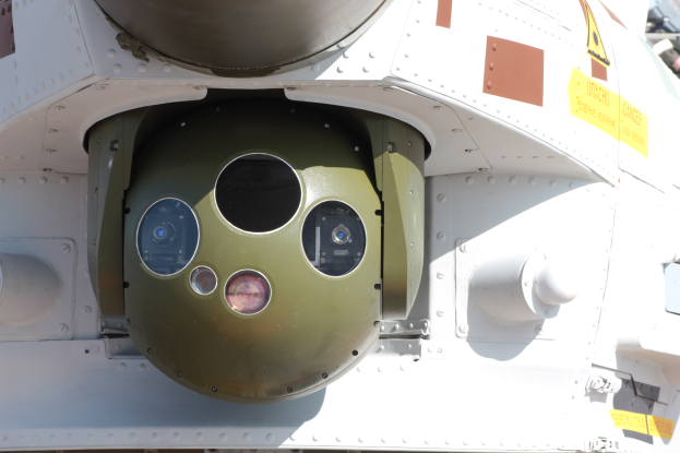 Nahaufnahme eines Militärfahrzeugs mit einer grün-weißen runden Rakete, die seitlich angebracht und von einem Metallrahmen gesichert ist.