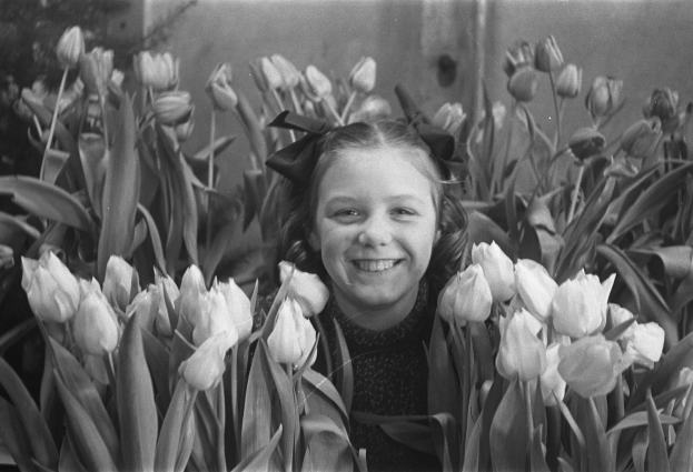 Schwarz-weiß-Foto eines lachenden Mädchens in einem Feld voller leuchtender Tulpen.