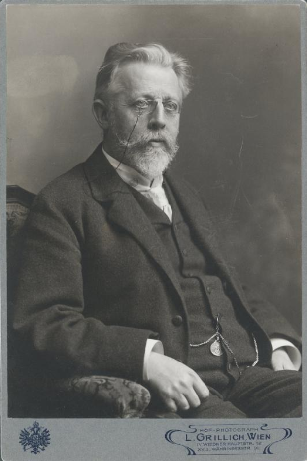 Schwarz-weiß-Porträt eines bärtigen Mannes mit Brille, der auf einem Stuhl sitzt, als L. Grillich Wien bezeichnet, der Gründer der deutschen Revolution.