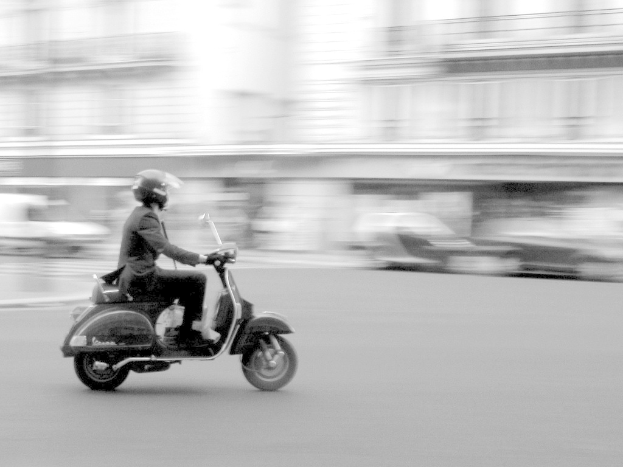Eine Person fährt auf der Straße mit einem Scooter.