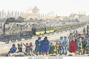 Eine Gruppe von Menschen steht um einen Zug auf einem Gleis, einige sitzen im Zug und andere auf dem Boden, vor Gebäuden und Bäumen, mit dem Text "Ludwigs-Eisenbahn, der erste Bahnhof in Deutschland" unten.