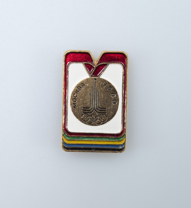 Ein weißer Abzeichen von den Olympischen Winterspielen 1980 in Moskau, Russland, mit einem bunten Design und der Aufschrift 'Olympische Spiele'.
