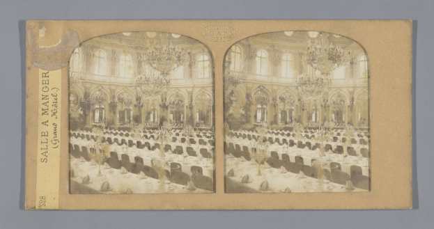 Ein altes Foto eines prunkvollen Hotel-Speisesaals mit Tischen, Stühlen, Kristalllüstern und Fenstern, auf dem links der Text 'Sale a Manger, Grand Hotel' steht.