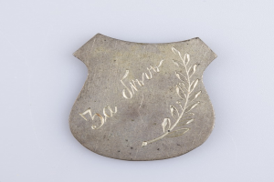 Ein silbergerändertes Abzeichen mit einem Lorbeerkranz, beschriftet mit "50-jähriges Jubiläum", vor einem weißen Hintergrund.