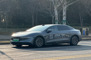 Ein Tesla Model X fährt auf einer Straße in China, umgeben von Bäumen auf beiden Seiten und einem Mülleimer auf der rechten Seite.