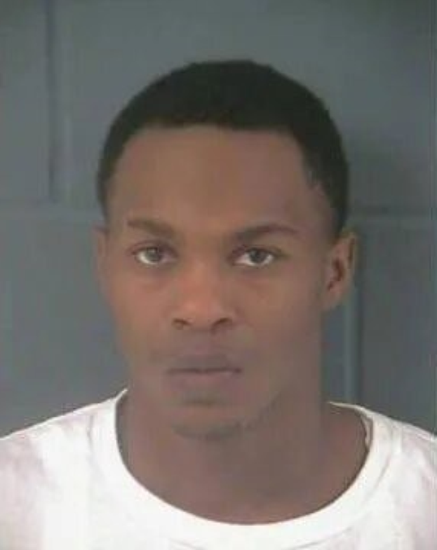 Bild eines Mannes in einem weißen T-Shirt an einer Wand, verdächtigt im Mord an einem jungen Mann festgenommen wegen sexuellen Missbrauchs.