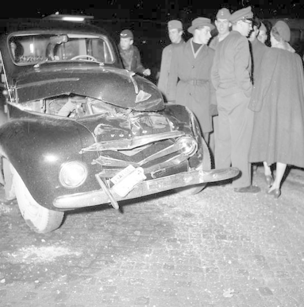 Schwarz-Weiß-Bild Eines Schwer Geschädigten Autos An Der Straße Mit Einer Gruppe Von Menschen, Die Es Begutachten.